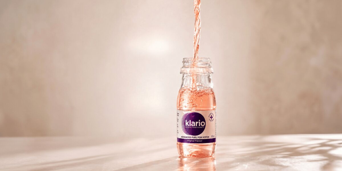 Klario Original Flavour being poured into a 130ml bottle on a sunlit marble surface