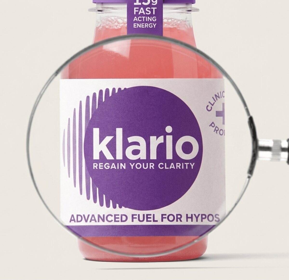 A magnifying glass held over a bottle of Klario, enlarging the label's logo and 'Advanced fuel for hypos' wording